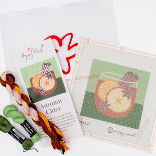 Poppy Monk Autumn Cider needlepoint canvas shown with kit threads, a glass of cider with orange slices on green