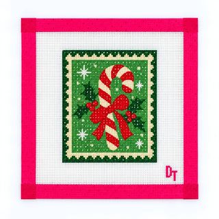 Duo Threads Candy Cane Cutie needlepoint canvas, 18 mesh mini design of a red and white candy cane with a big red bow, holly and evergreen inside a green postage stamp border